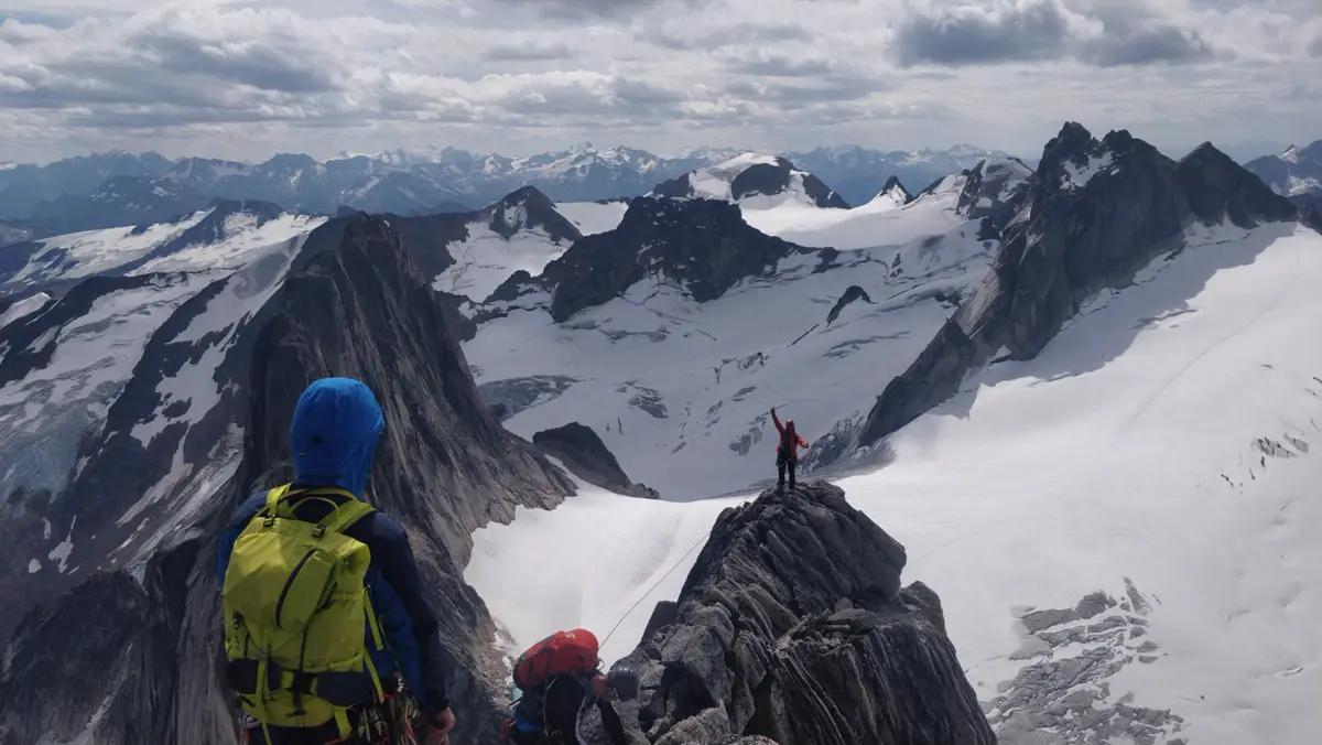 A climber looks across a glacier to another climber on a rocky pinnacle