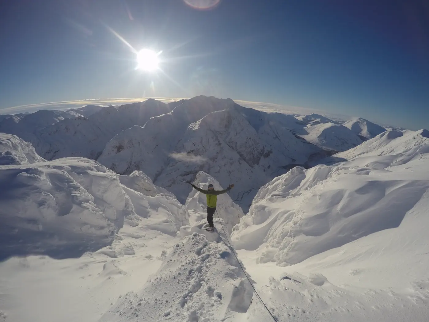 Tom Shooter with arms outstretched on a snowy summit